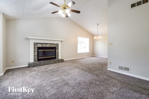 A spacious room with a fireplace and a ceiling fan.
