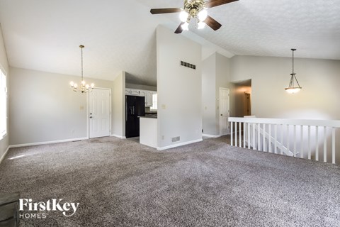 A spacious living room with a ceiling fan and a chandelier.