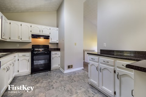 A kitchen with white cabinets and black appliances.