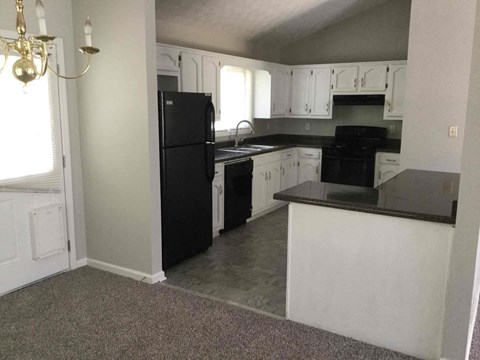 A kitchen with black appliances and white cabinets.
