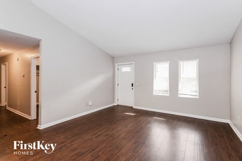 a living room with wood floors and white walls and a door