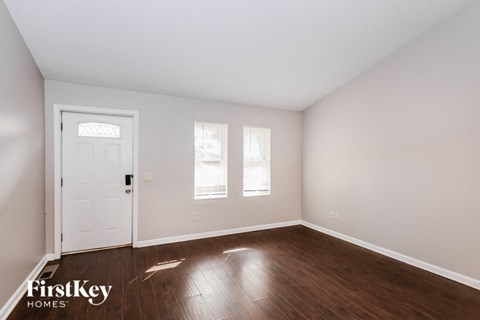 a bedroom with white walls and wood floors and a white door