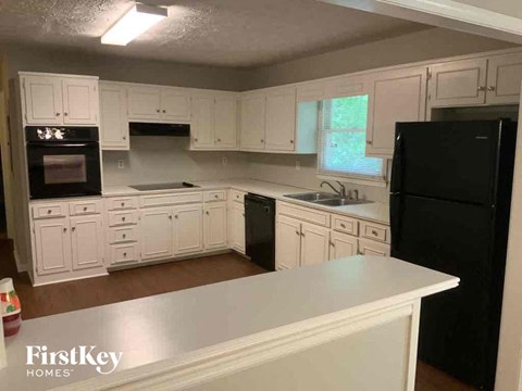 A kitchen with white cabinets and a black refrigerator.