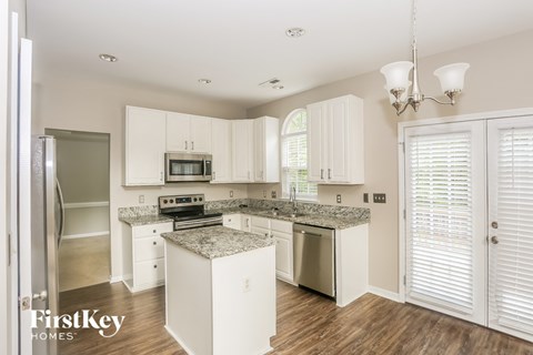 a kitchen with white cabinets and marble counter tops
