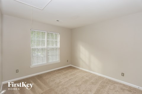 a bedroom with a large window and a carpeted floor