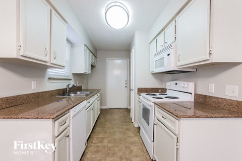 a kitchen with white cabinets and white appliances and granite counter tops