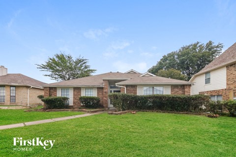 a brick house with a grass lawn and a sidewalk