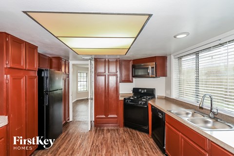 a kitchen with wooden cabinets and black appliances and a sink