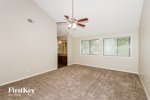 a spacious living room with carpet and a ceiling fan