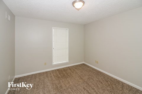 a spacious bedroom with carpet and a window