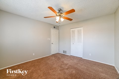 the spacious living room with ceiling fan and carpet