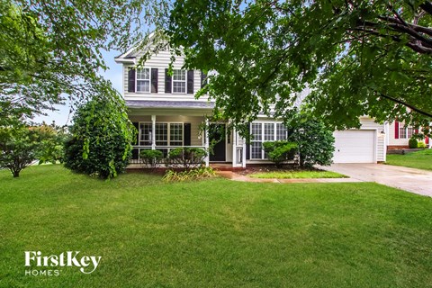 a house with a lawn and trees in front of it