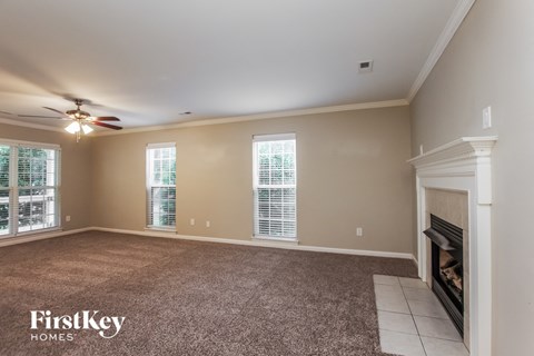 an empty living room with a fireplace and a ceiling fan