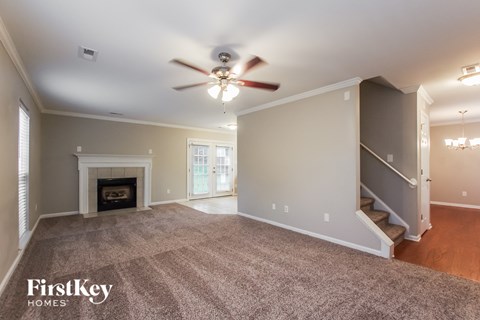 an empty living room with a ceiling fan and a fireplace