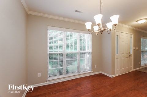 an empty dining room with a large window and a chandelier