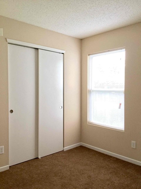 A room with a white door and a window with blinds.