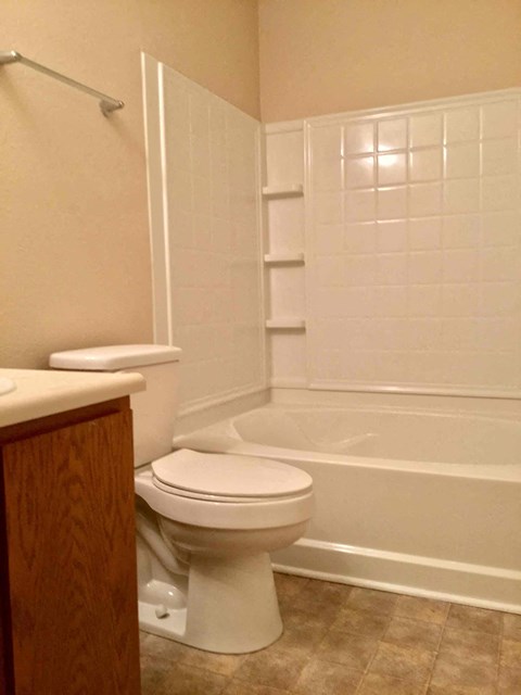 A white toilet in a bathroom with a white tiled shower.