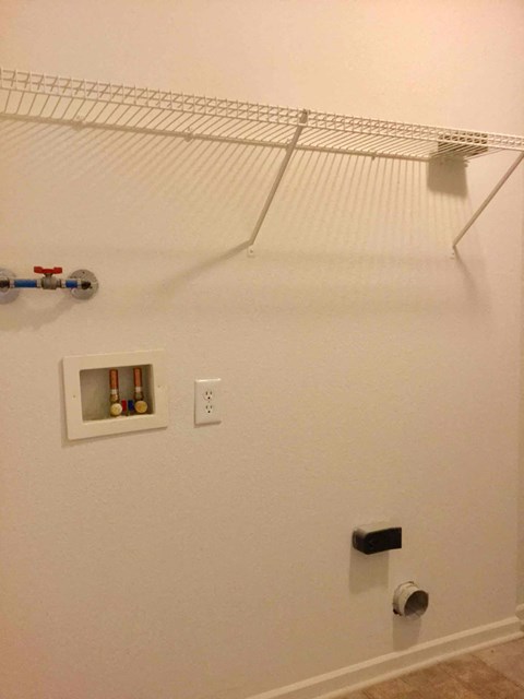 A white wall with a shelf and a black object on it.