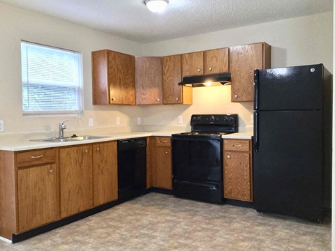A kitchen with black appliances and wooden cabinets.