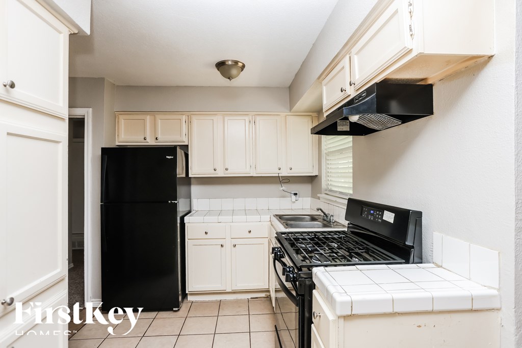A kitchen with black appliances and white cabinets.