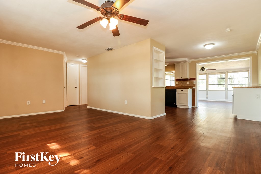 A spacious room with a ceiling fan and wooden flooring.