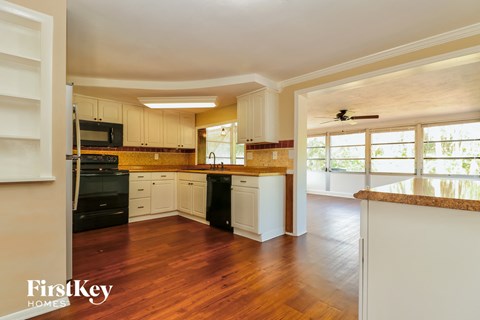 A kitchen with wooden floors and white cabinets.