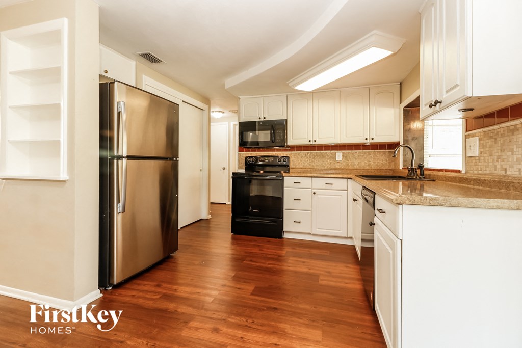 A kitchen with wooden floors and a stainless steel refrigerator.