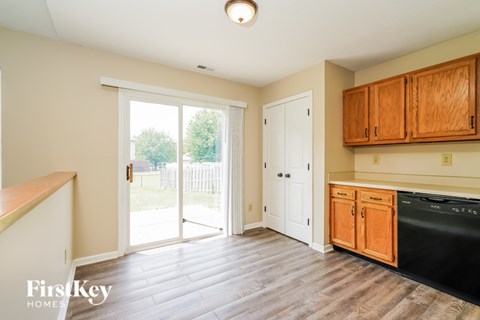 A kitchen with wooden cabinets and a black dishwasher.