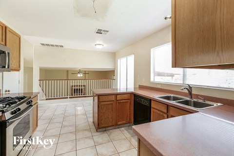A kitchen with a stove top oven, a sink, and a window.