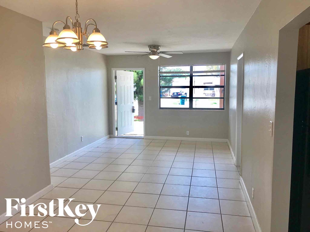 an empty living room with a ceiling fan and a tiled floor