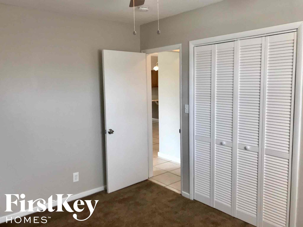 a closet with white shutters and a door to a bathroom