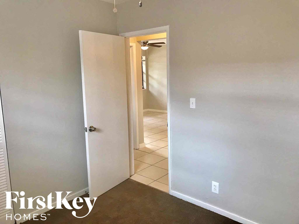 a room with a door open to a hallway and a door to a closet