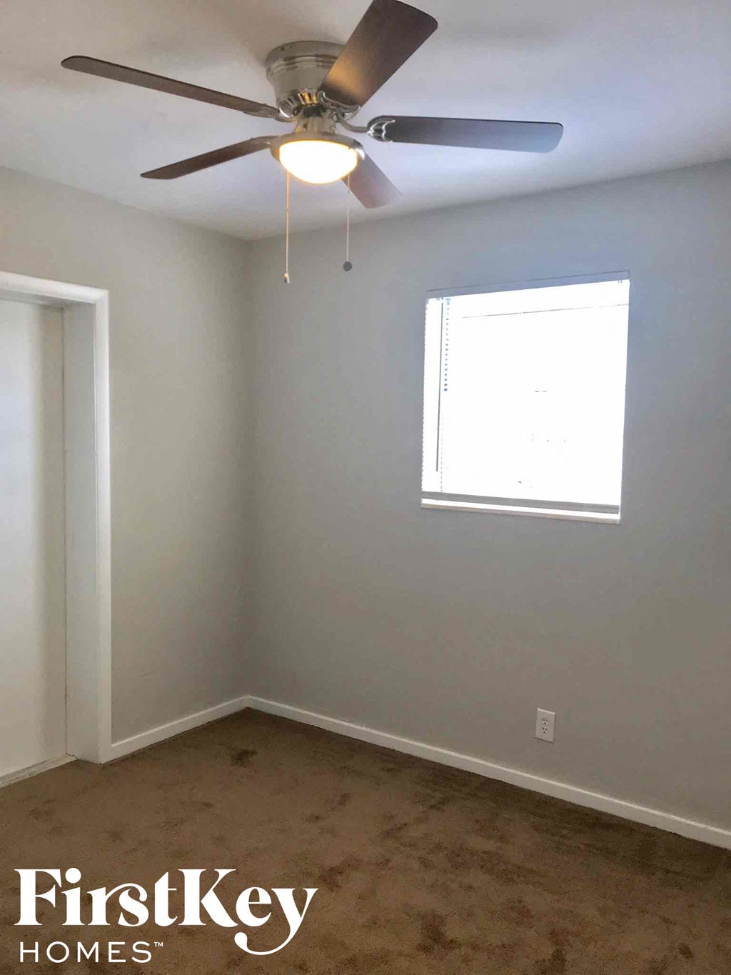 a empty room with a ceiling fan and a window