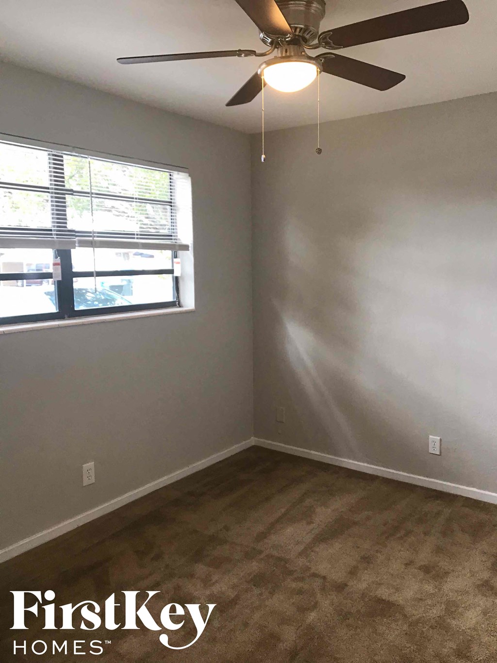 an empty room with a ceiling fan and a window