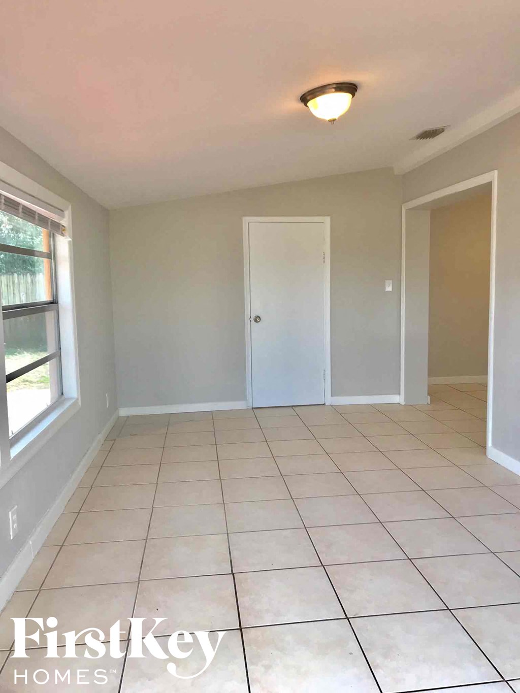 a living room with a tiled floor and a door to a closet