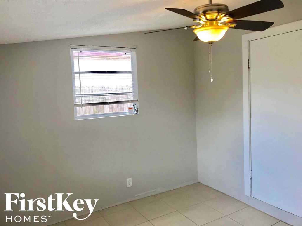 an empty room with a ceiling fan and a window