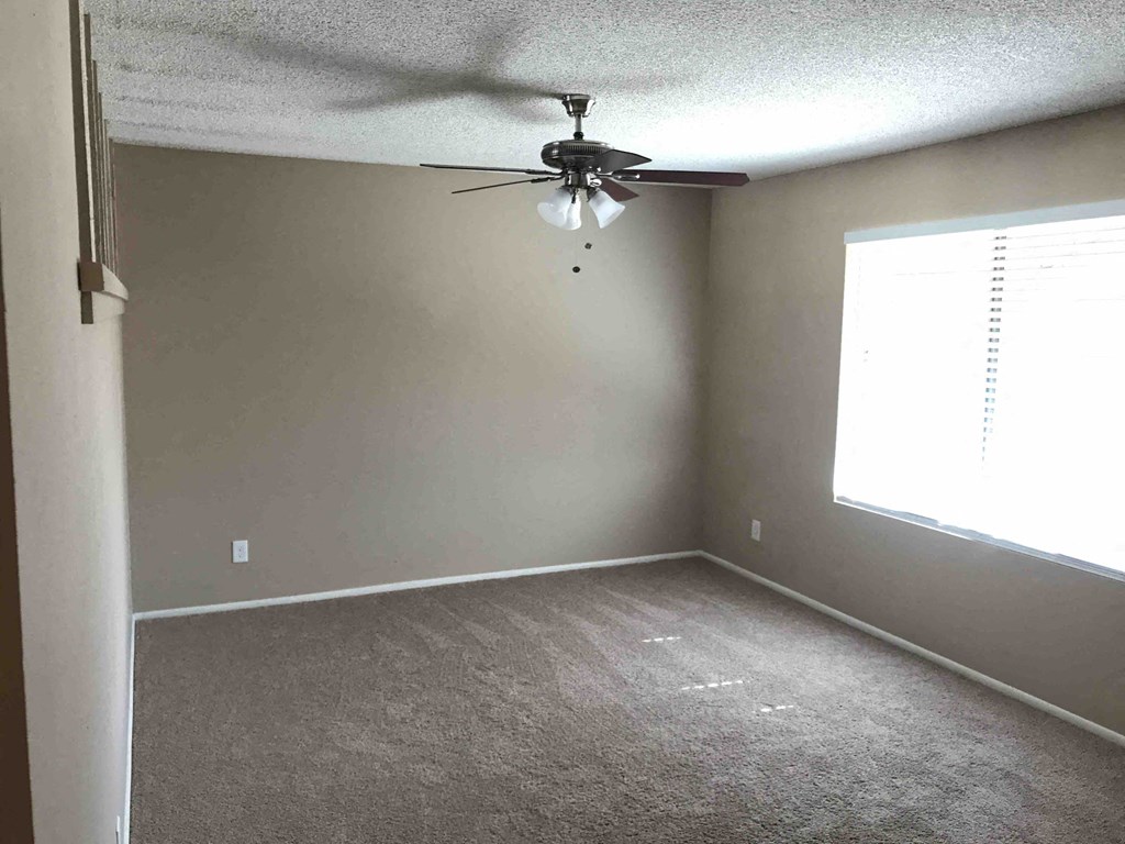 A room with a ceiling fan and a window.