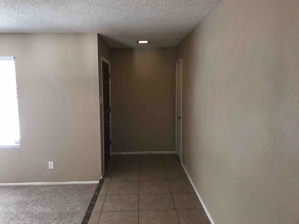 A room with a brown door and a window on the left.