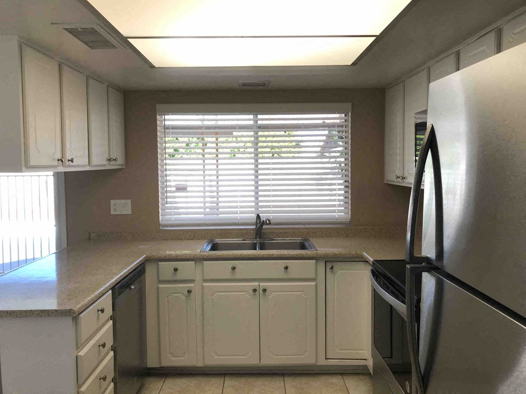 A kitchen with white cabinets and a stainless steel refrigerator.