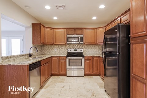A kitchen with wooden cabinets and a black refrigerator.