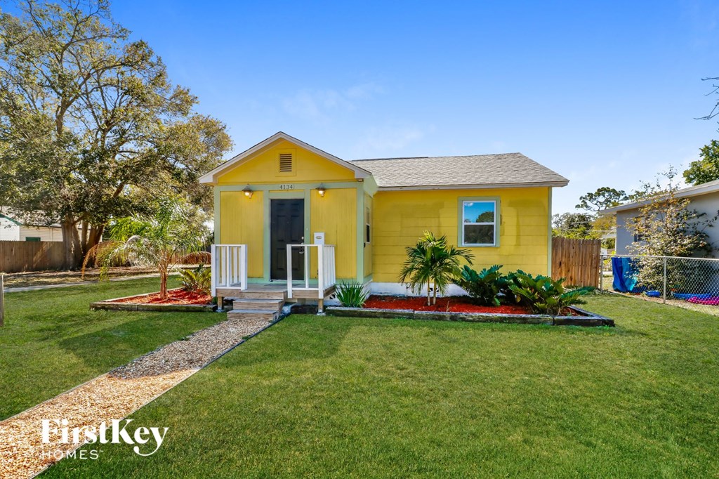 a small yellow house with a lawn and a porch