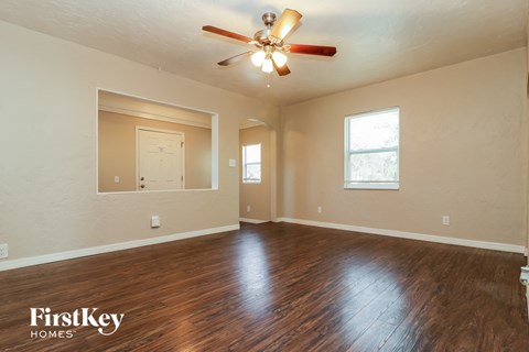 the living room of an empty house with wood floors and a ceiling fan