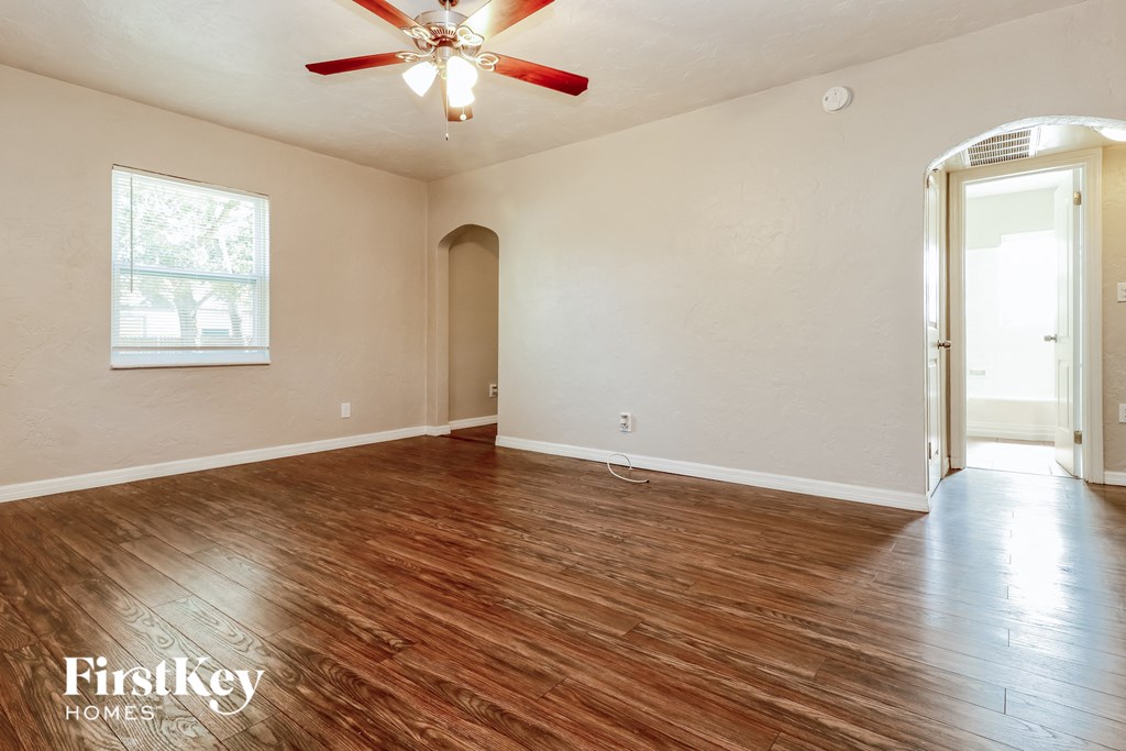 an empty living room with wood flooring and a ceiling fan