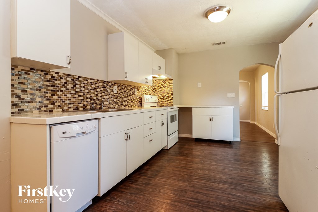 a kitchen with white cabinets and a wood floor