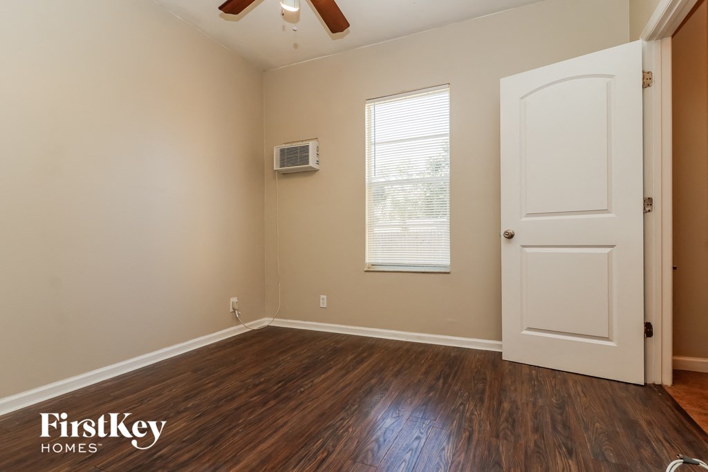 the living room of an empty house with wooden floors and a white door