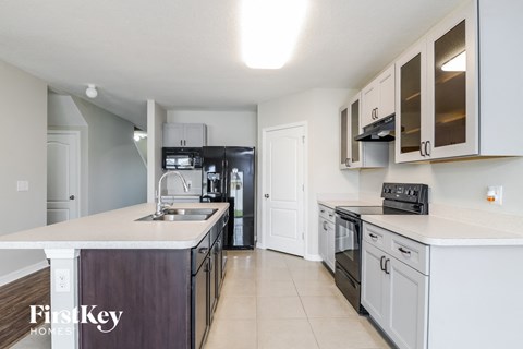 A kitchen with a white counter top and a stove top oven.