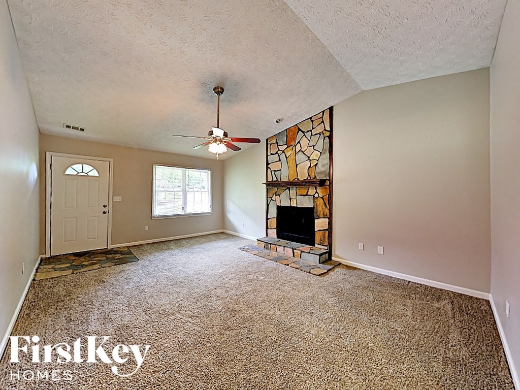 an empty living room with a fireplace and a ceiling fan