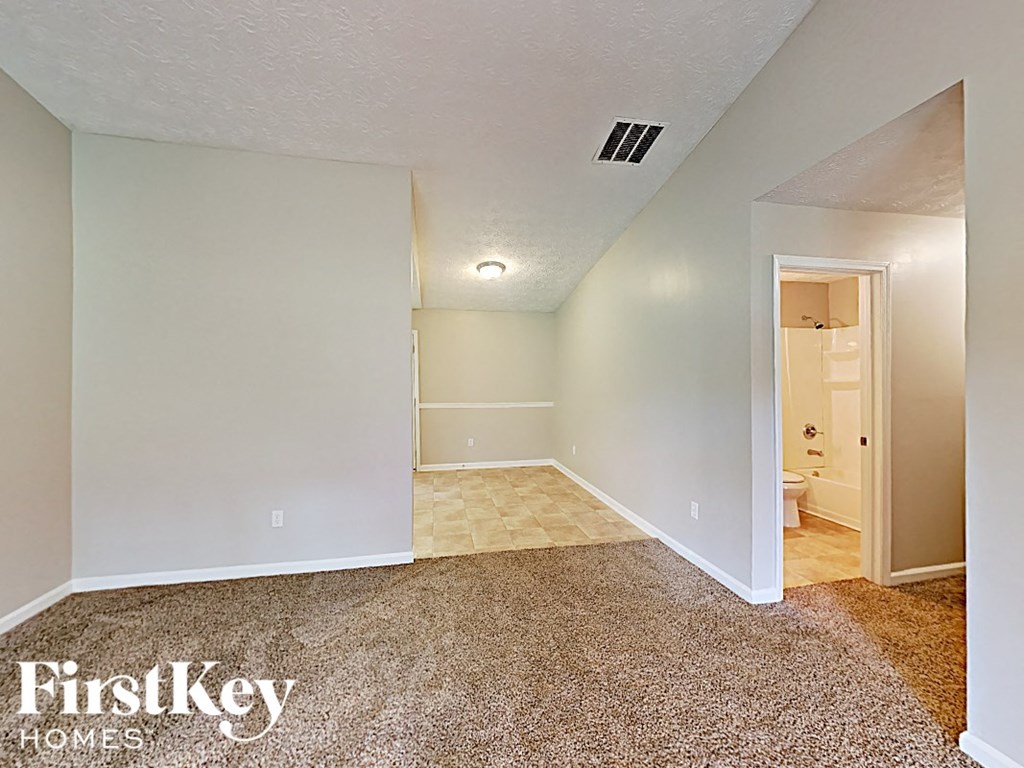 an empty living room with carpet and a bathroom