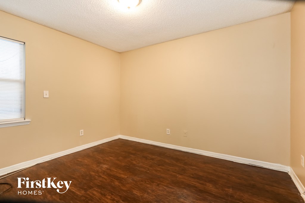 the living room of an empty house with wood flooring and a window