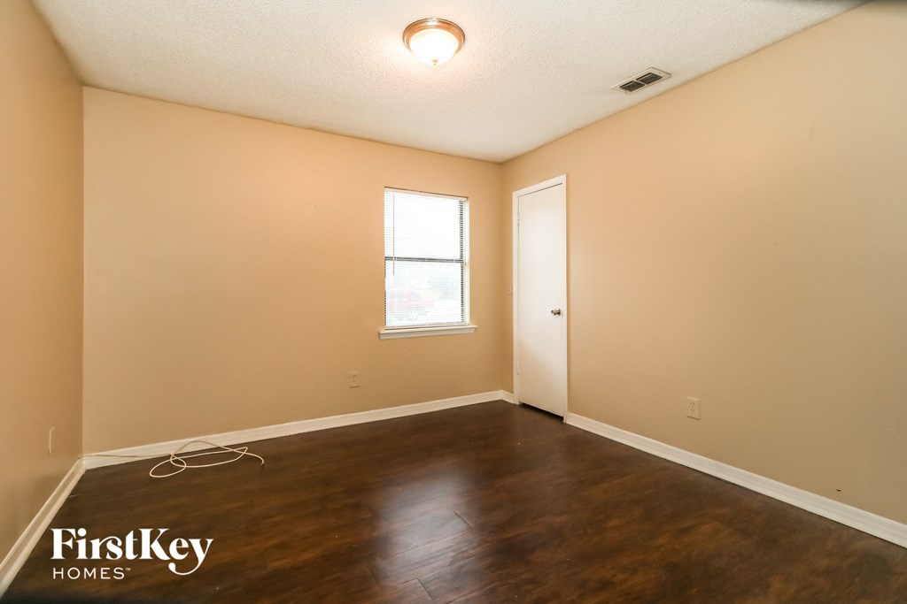 the living room of an empty house with wooden floors and a window
